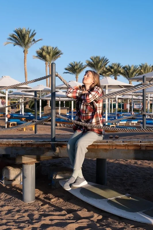 Młoda kobieta siedząca na molo przy wschodzie słońca