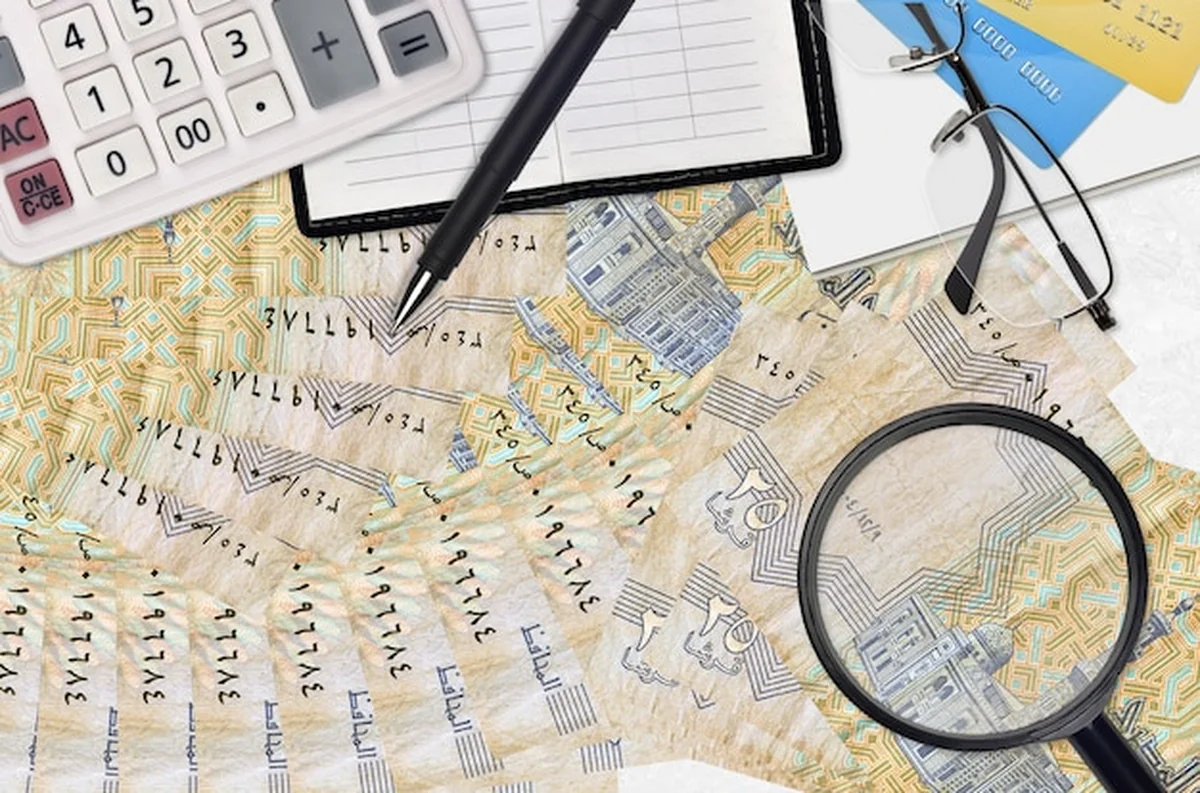 Kalkulator z okularami i długopisem obok egipskich rachunków