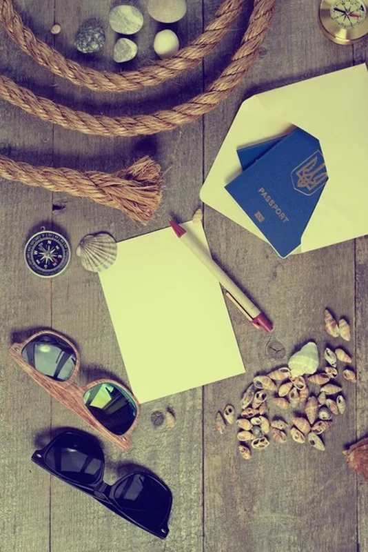 Przedmioty podróżne na drewnianym stole z notatnikiem