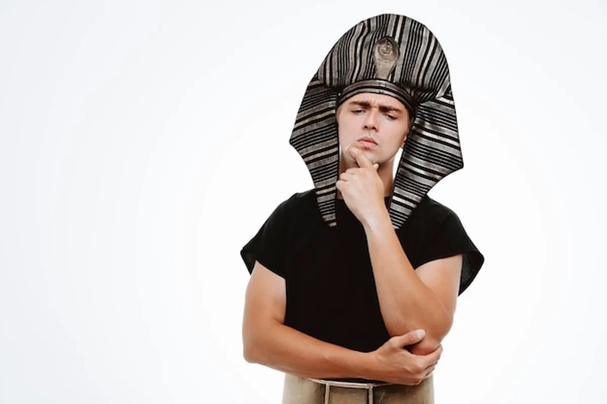 Mężczyzna w starożytnym egipskim stroju z zamyślonym wyrazem twarzy, myślący ręką na brodzie na białym