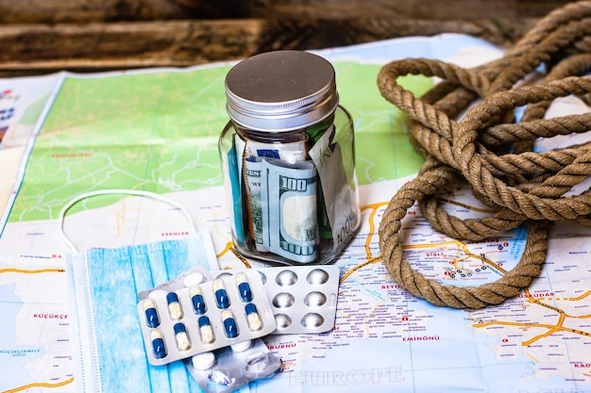 Kompozycja z banknotami, pigułkami i maską chirurgiczną na mapie