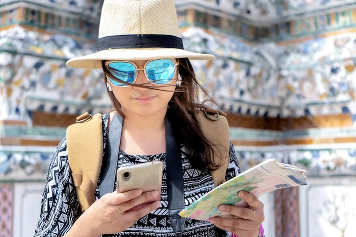 Azjatycka turystka zwiedza świątynię Wat Arun w Bangkoku, korzysta ze smartfona do wyszukiwania informacji turystycznych