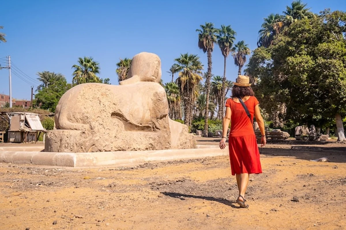 Młoda turystka w czerwonej sukience zwiedzająca Sfinksa z Memphis w Kairze