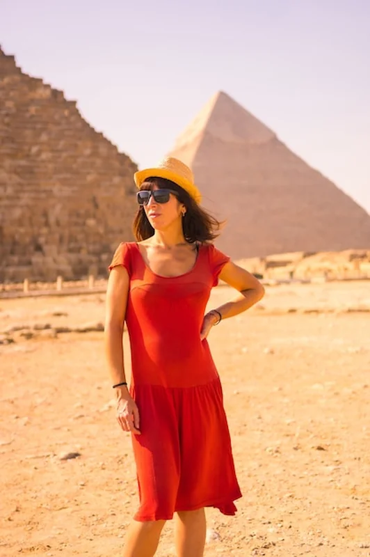 Młoda dziewczyna na piramidzie Cheopsa w czerwonej sukience