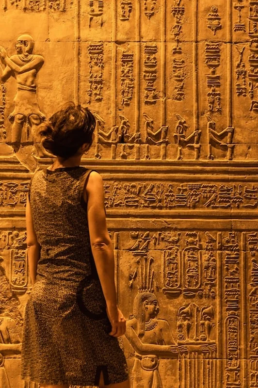 Młoda kobieta ogląda egipskie rysunki i hieroglify w świątyni Kom Ombo