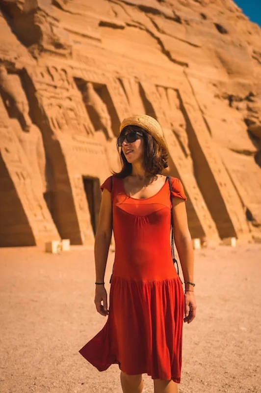 Młoda dziewczyna w czerwonej sukience przy świątyni Nefertari w Egipcie