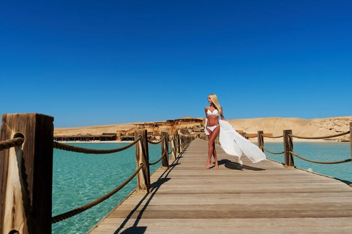 Młoda kobieta w białym pareo na molo obok morza