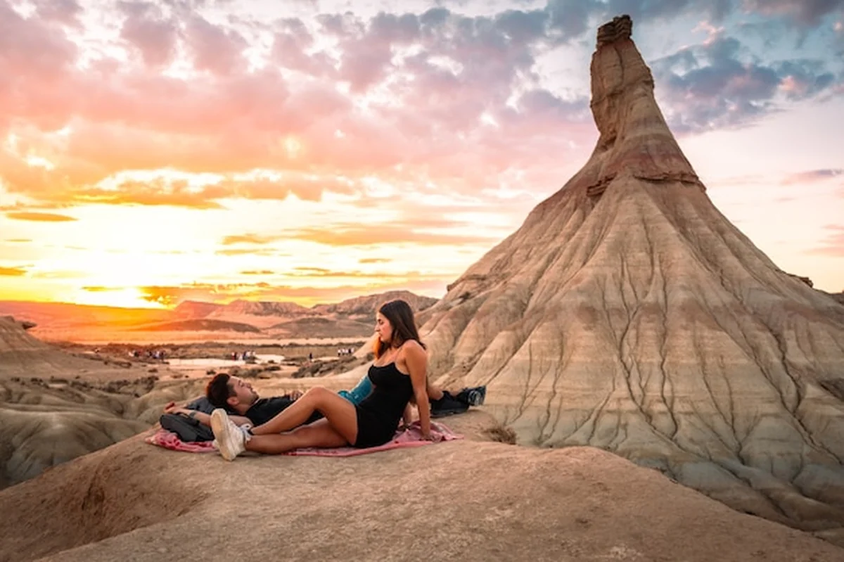 Młody mężczyzna i młoda kobieta oglądający zachód słońca na pustyni Bardenas Reales