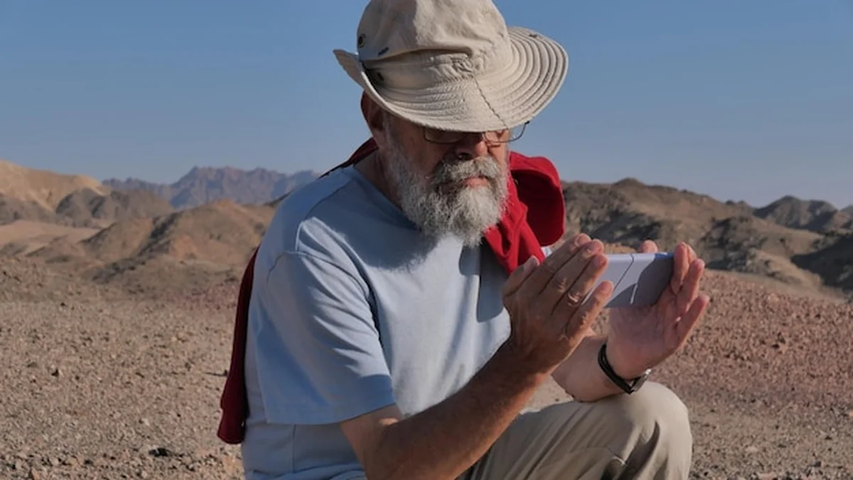 Starszy mężczyzna używający telefonu komórkowego na pustyni