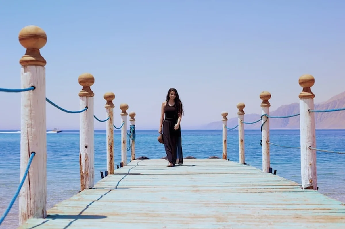 Egipska dziewczyna spaceruje po drewnianym molo w lagunie Dahab