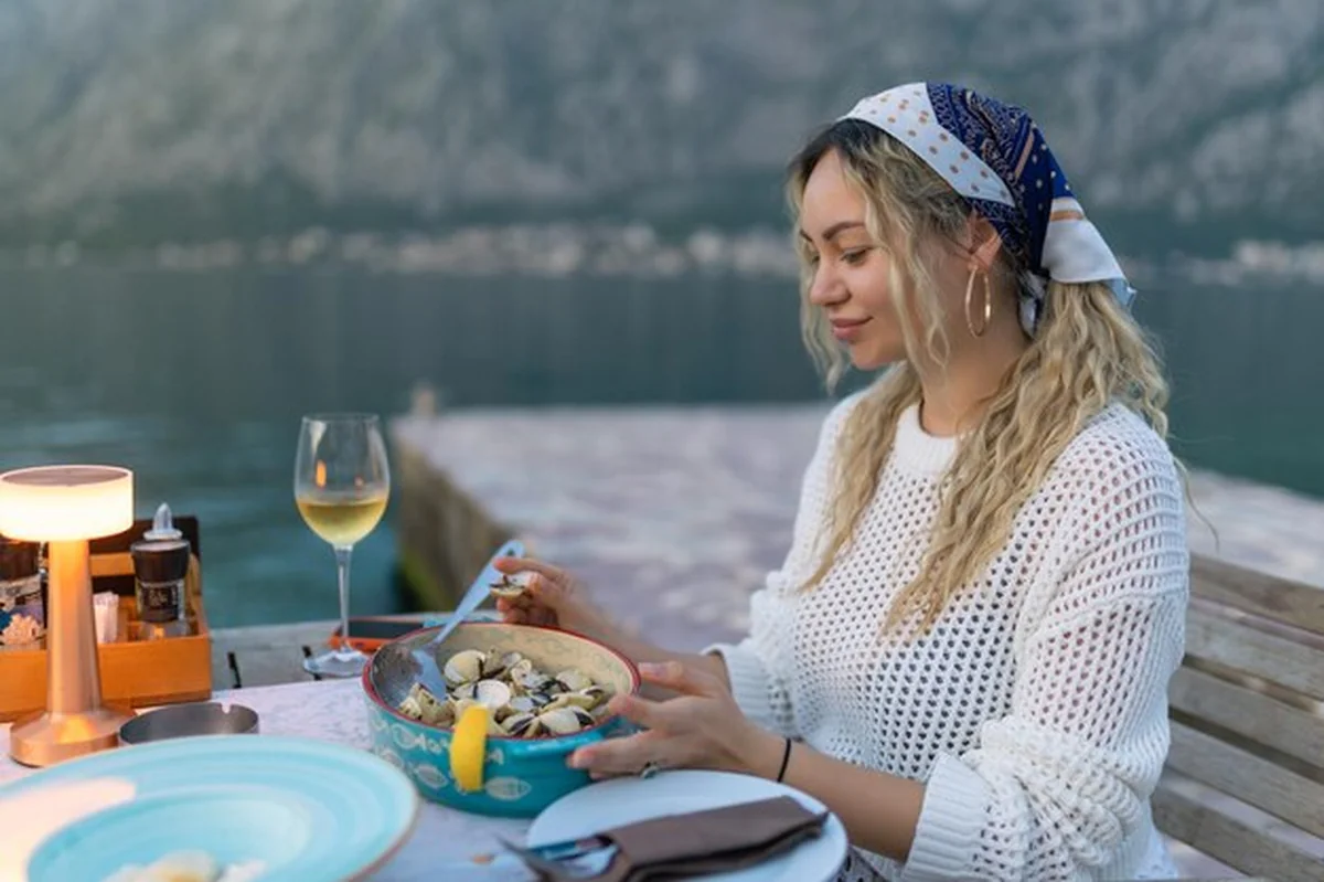 Kobieta jedząca muszle na tarasie restauracji