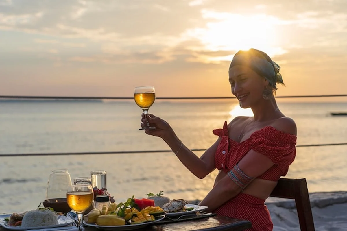 Młoda kobieta jedząca kolację w restauracji nad morzem o zachodzie słońca