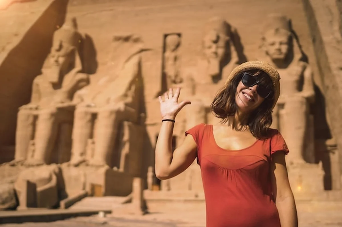 Młoda turystka w czerwonej sukience w świątyni Abu Simbel w południowym Egipcie