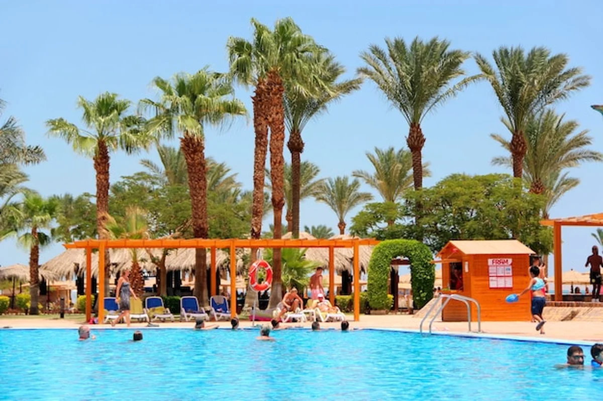 Basen z palmami wodnymi i hotel. Ludzie w egipskim kurorcie odpoczywają i cieszą się wakacjami w basenie